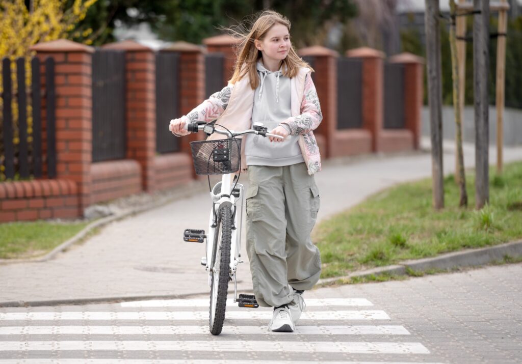 Girl Crosses Road On Pedestrian Crossing With Bicycle